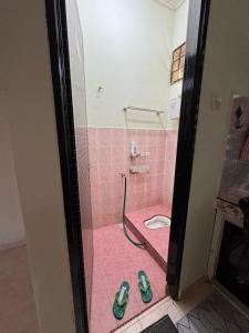 Baño rosa con aseo y un par de zapatos en Syurgaku Homestay Tanah Merah, en Tanah Merah