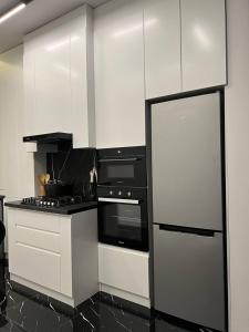 a kitchen with white cabinets and a black refrigerator at Hi-Tech Apartment in Tashkent