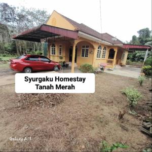 Syurgaku Homestay Tanah Merah في تاناه ميراه: منزل فيه سيارة متوقفة أمامه