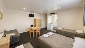 a room with two beds and a table and a kitchen at Coachman Hotel Motel in Parkes