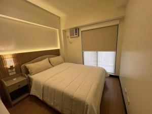 een kleine slaapkamer met een bed en een raam bij Estellar Resort Condotel in Manilla