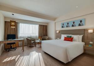 a hotel room with a large white bed and a desk at Greenpark Visakhapatnam in Visakhapatnam
