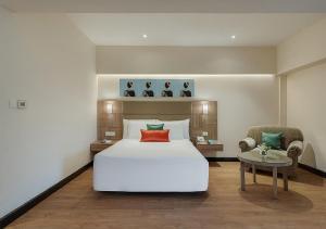 a bedroom with a large white bed and a chair at Greenpark Visakhapatnam in Visakhapatnam