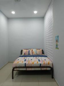 Bett in einem Zimmer mit einer weißen Wand in der Unterkunft Cempaka Homestay Batu Pahat 93 in Batu Pahat