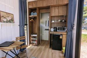 a kitchen with a refrigerator and a table and a microwave at Tiny House 10 at Grampians Edge in Dadswells Bridge