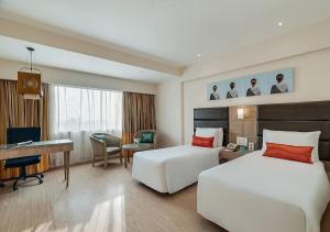 a hotel room with two beds and a desk at Greenpark Visakhapatnam in Visakhapatnam