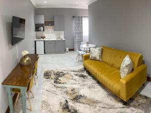- un salon avec un canapé jaune et une table dans l'établissement StaySure Guesthouse, à Alberton