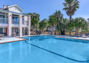 a large swimming pool with palm trees and a house at Life Can Be A Beach in Galveston