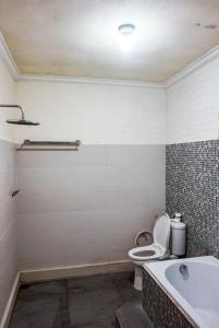 een badkamer met een toilet, een wastafel en een bad bij Homestay Jro Mangku Gede House in Penginyahan