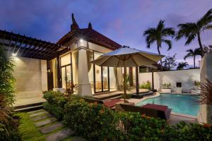 a house with a swimming pool and an umbrella at The Club Villas Seminyak in Seminyak