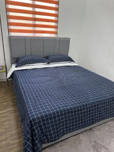 a bed in a bedroom with a blue plaid blanket and pillows at Seriemas Angler Venture Homestay in Sepang