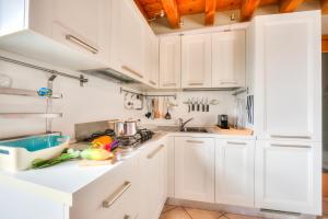 a white kitchen with white cabinets and vegetables on the counter at Faby House On Hilly Area & Lake View - Happy Rentals in Gargnano