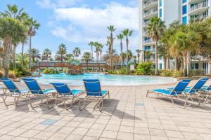 a pool at the resort with blue chairs and palm trees at Entire Condo - Palms of Destin Paradise in Destin