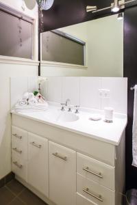 a white bathroom with a sink and a mirror at Indulge Homes - 77 Olive in Mildura