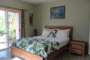 um quarto com uma cama com um edredão verde e branco em Rutaki Retreat em Rarotonga