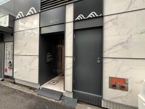 un edificio con una puerta negra a un lado. en ELLE Namba 6 en Osaka