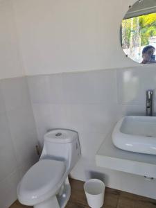 Baño blanco con aseo y lavamanos en Casa Mochileros Anonimos, en El Guayabo