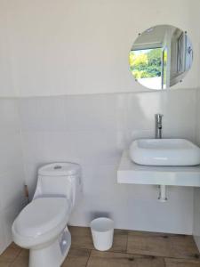 Baño blanco con aseo y espejo en Casa Mochileros Anonimos, en El Guayabo