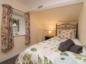 a bedroom with a bed with a floral bedspread at Nook Cottage in Keswick