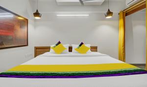 Una cama blanca con almohadas amarillas y verdes. en Abrigo Delamar, en Kozhikode