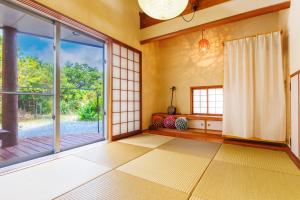 an empty room with a large glass door and a window at Cottage Muinochichi in Motobu