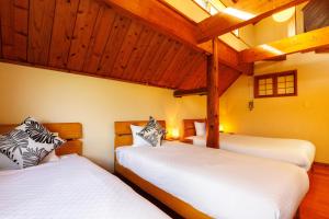 two beds in a room with wooden ceilings at Cottage Muinochichi in Motobu +41 photos
