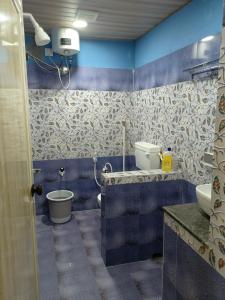a blue bathroom with a toilet and a sink at Talpona Beach Studios in Magdāl