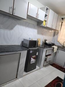 a small kitchen with white cabinets and a microwave at Wanderlust Haven in Thika