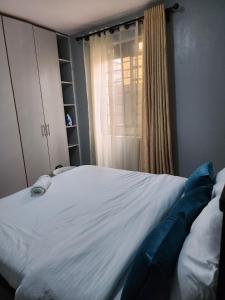 - une chambre avec un grand lit blanc et une fenêtre dans l'établissement Wanderlust Haven, à Thika