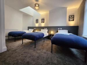three beds in a room with blue sheets at Goodison Accommodation in Liverpool