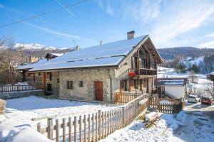 a stone house with a fence in the snow at Paquita's Home - San Sicario Borgo - Happy Rentals in Cesana Torinese