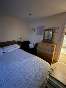a bedroom with a bed and a dresser and a mirror at Broxbourne Two-Bedroom Apartment Close To Amenities in Hoddesdon