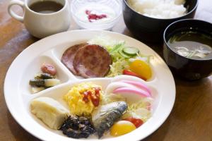 ein weißer Teller mit Lebensmitteln auf einem Tisch in der Unterkunft Iwaki Prince Hotel in Iwaki