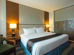 セブシティにあるLex Hotel Cebuの大きなベッドと椅子が備わるホテルルームです。