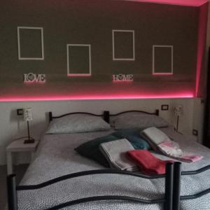 - une chambre dotée d'un lit avec une lumière rose au-dessus dans l'établissement villa verde bed and breakfast, à Uggiate