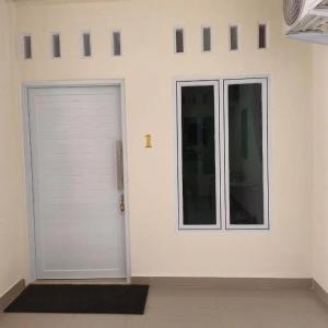 un garage blanc avec une porte et une fenêtre dans l'établissement Lovetogy homestay, à Sungailiat