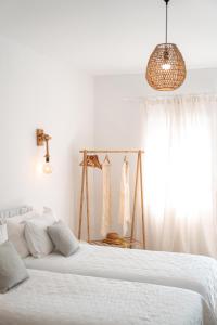 a white bedroom with two beds and a window at La Stella Stay in Glastros