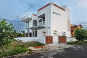 a white house with a gate and a driveway at Orchid Escape by JadeCaps 3BHK Villa Near Airport & Nandi Hills No Pool in Devanahalli-Bangalore