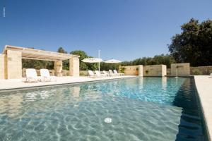 una piscina con sillas blancas y una piscina en Agriturismo La Turrita, en SantʼAndrea
