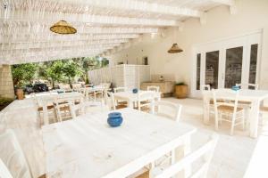 a patio with white tables and white chairs at Agriturismo La Turrita in SantʼAndrea