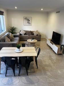 sala de estar con sofá, mesas y TV en Townhouse in Hope Island, en Gold Coast