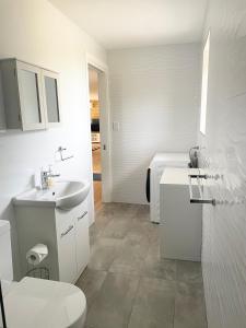 a white bathroom with a toilet and a sink at Sandstone Family Apartment in Grindelwald