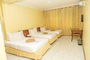 una camera d'albergo con 3 letti e una scrivania di Holiday Express Hotel Kampala a Kampala