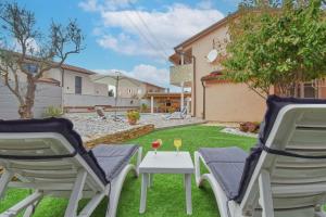 a patio with two chairs and a table with wine glasses at Holiday House Amna in Kaldanija