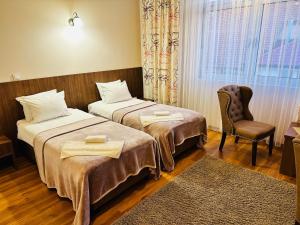 a hotel room with two beds and a chair at HOTEL MINERO in Tuzla