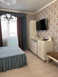 a bedroom with a bed and a flat screen tv at Гостинично-банный комплекс Майами Люкс in Kostanay