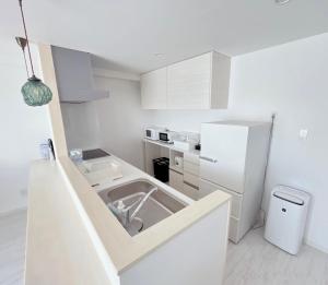 a white kitchen with a sink and a refrigerator at COZYSTAY IN トゥリバー宮古島 in Miyako-jima