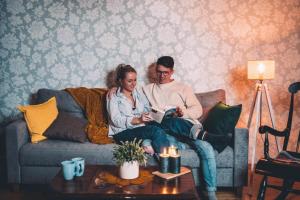 a man and woman sitting on a couch reading a book at Kärdla Retrovisiit Helmi in Kärdla