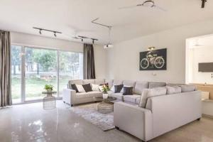 a living room with white furniture and a large window at Golf View Home by JadeCaps 4BHK with Breakfast in Hosūr