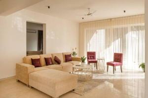 a living room with a couch and a table and chairs at Golf View Home by JadeCaps 4BHK with Breakfast in Hosūr